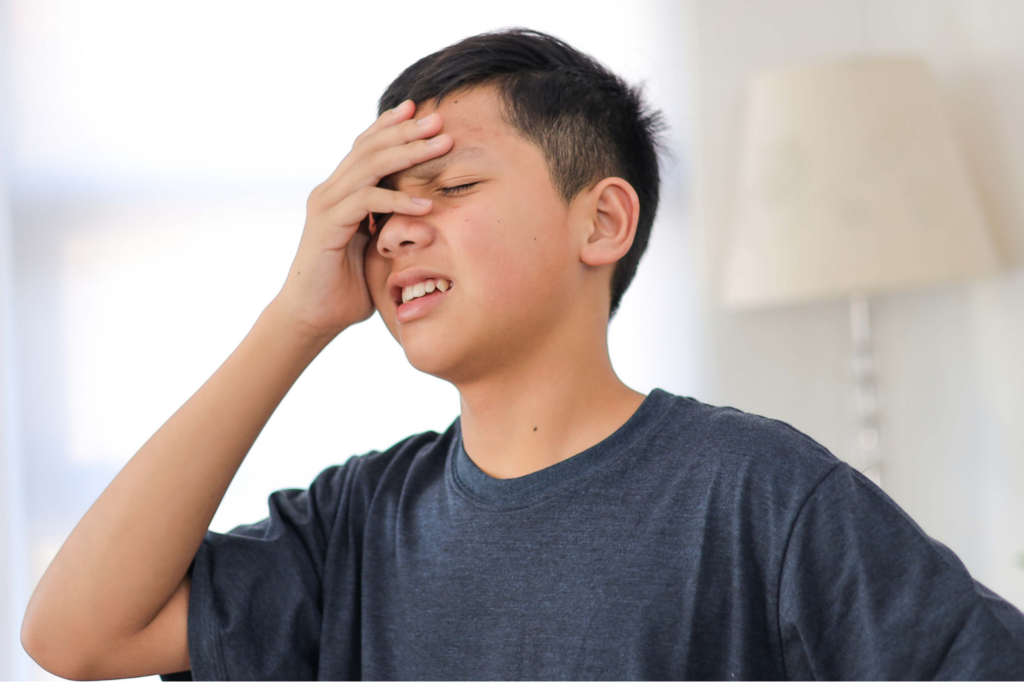 Child with a headache at a school desk, illustrating migraines when school starts